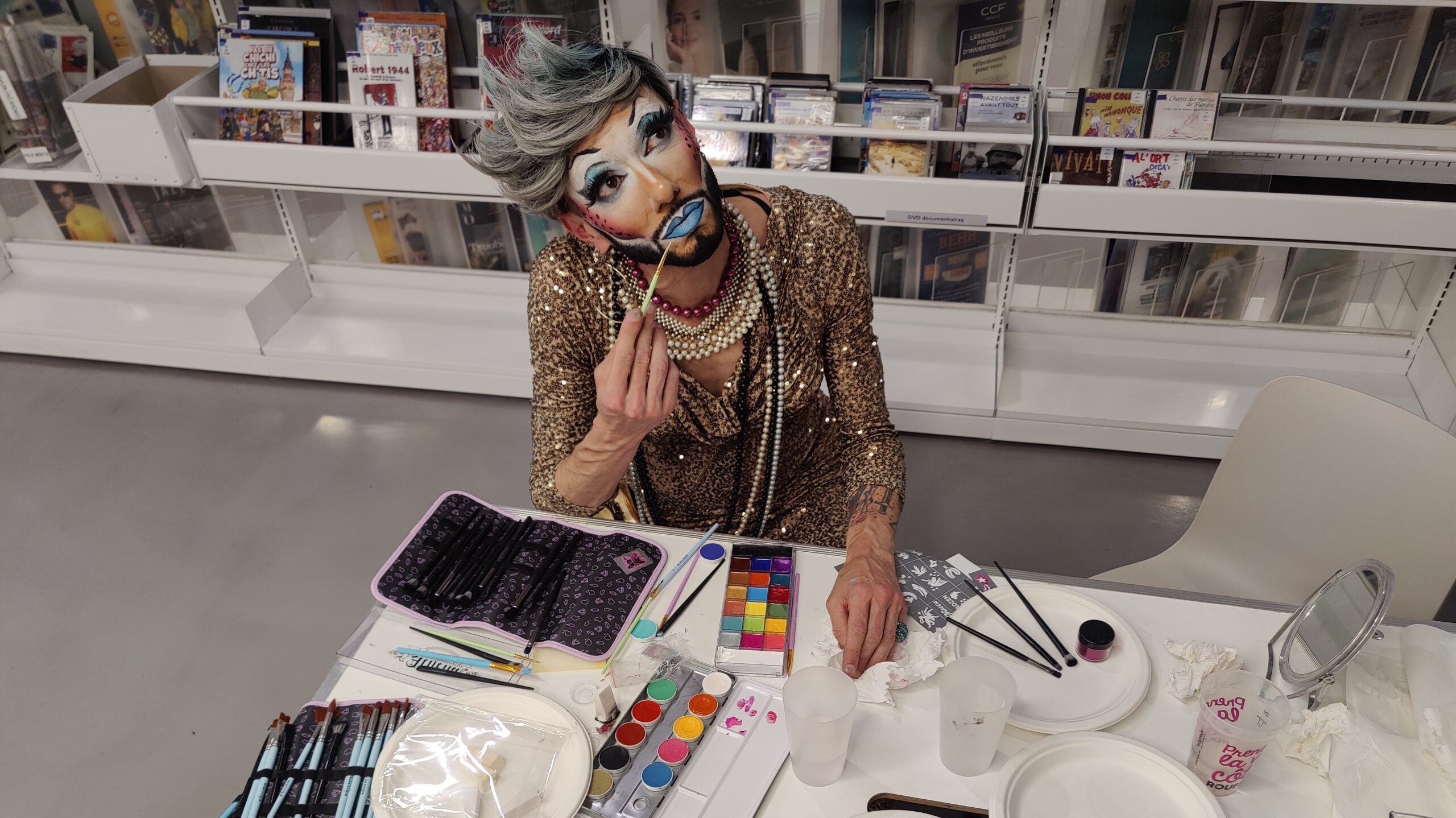 Artiste drag en tenue dorée, pinceau à la main